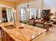 Open concept kitchen with granite island and barstool seating flowing to dining area and living room at 9238 Viaggio Way, Highlands Ranch, CO 80126