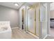 Bright bathroom featuring a tile tub, gold-framed shower and wood-look floors with a view into an adjacent room at 10183 Grove Loop # D, Westminster, CO 80031