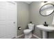 Stylish powder room features a modern pedestal sink, a round mirror, and neutral wall paint at 10183 Grove Loop # D, Westminster, CO 80031