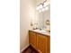 A well-lit powder room featuring wood cabinets, a sink, and a decorative lighting fixture at 12000 Horseshoe Ln, Parker, CO 80138
