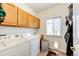 Bright laundry room featuring a washer, dryer, storage cabinets, and a window at 12000 Horseshoe Ln, Parker, CO 80138
