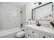 Updated bathroom with sleek white vanity, modern fixtures, and a shower/tub combination with marble tiling at 3247 S Newland St, Denver, CO 80227