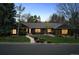 Dusk view of brick single-story with inviting glowing windows and mature trees at 5290 Nassau E Cir, Cherry Hills Village, CO 80113