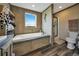 Bright bathroom features a built-in bathtub with a window, a walk-in shower, toilet, and plenty of shelving for storage at 4255 S County Road 185, Byers, CO 80103