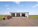 Large metal outbuilding with three bays and tractor, set against a grassy field at 4255 S County Road 185, Byers, CO 80103