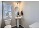 A bathroom features a pedestal sink, round mirror, and a window with blinds at 296 N Newcastle Way, Aurora, CO 80018