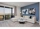 Comfortable living room featuring a large sectional sofa, access to balcony and contemporary decor with eye-catching blue accent wall at 10866 Lyric St, Lone Tree, CO 80134