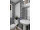 Stylish powder room with a sleek pedestal sink, toilet, black and white patterned wallpaper, and minimalist decor at 10866 Lyric St, Lone Tree, CO 80134