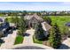 An aerial view of a landscaped two-story home, with a circular driveway, on a golf course near the mountains at 1287 Buffalo Ridge Rd, Castle Pines, CO 80108