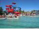 Community swimming pool featuring water slides and people socializing with their pets on a sunny day at 19725 Rosewood Ct, Parker, CO 80138