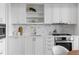 All white kitchen with stainless appliances, marble backsplash and bright light at 1750 Wewatta St # 830, Denver, CO 80202