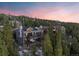 Multi-level home nestled in a forest with balconies, and a hot tub, all against a backdrop of a colorful sunset sky at 85 Uncle Sam Lode, Breckenridge, CO 80424