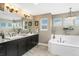 Bright bathroom features dual sinks, granite counters, chandelier and soaking tub at 19429 W 88Th Dr, Arvada, CO 80007