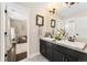 Modern bathroom with dual sinks, black cabinets, and tile floors at 19429 W 88Th Dr, Arvada, CO 80007