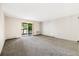 Spacious living room with neutral carpet, sliding glass door to outdoor patio, and air conditioning unit at 3082 S Wheeling Way # 202, Aurora, CO 80014