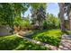 Serene backyard with a lush lawn, mature trees, garden beds, and a charming hammock for relaxation at 400 Holly St, Denver, CO 80220