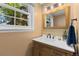 Bright bathroom with a wood vanity, white countertop, and a large window offering natural light and greenery views at 400 Holly St, Denver, CO 80220