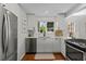 Bright kitchen featuring white cabinets, stainless steel appliances, and large windows at 400 Holly St, Denver, CO 80220
