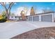 Charming single-Gathering home featuring an attached three-car garage, a brick chimney, and a long concrete driveway at 4145 Dudley St, Wheat Ridge, CO 80033