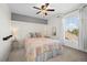 Cozy bedroom features decorative paneling, large window, ceiling fan, and plush bed at 4830 Monarch Dr, Firestone, CO 80504