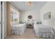 Cozy bedroom with two twin beds, natural light streaming in from a window, and simple, tasteful decor at 4830 Monarch Dr, Firestone, CO 80504