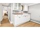 Stylish wet bar features white shaker cabinets, wood countertop, undermount sink, and glass storage at 3701 Eliot St, Denver, CO 80211