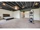Finished basement space with exposed ceiling, plush carpeting and an elliptical machine at 3620 Sandoval St, Brighton, CO 80601