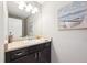 Powder room featuring a vanity with dark cabinets, a decorative mirror, and boat artwork at 22391 E Plymouth Cir, Aurora, CO 80016