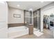 Bright bathroom featuring a soaking tub and shower with a glass enclosure and walk-in closet at 22391 E Plymouth Cir, Aurora, CO 80016