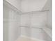 A walk-in closet with minimalist white walls, carpet and simple shelves and hanging rods at 4737 E Iliff Ave, Denver, CO 80222