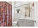 Bright bathroom features a modern vanity, shower with striking decorative curtain, and window at 8552 W San Juan Ave, Littleton, CO 80128