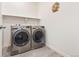 A laundry room featuring side-by-side washer and dryer units, shelving, and tile floors at 8552 W San Juan Ave, Littleton, CO 80128