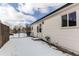 View of backyard with a small patio, white siding, chain link fence and snow covered ground at 808 Hanover St, Aurora, CO 80010