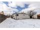 Wide shot of backyard with a shed, white siding, chain link fence and snow covered ground at 808 Hanover St, Aurora, CO 80010