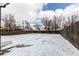 Wide shot of large, snow covered backyard with a wooden fence at 808 Hanover St, Aurora, CO 80010