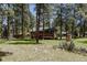 Scenic view of a cozy cabin surrounded by tall pines and a well-maintained yard with rock gardens at 29101 Drexel Spur, Evergreen, CO 80439