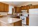 Efficient kitchen featuring a peninsula counter, wood cabinets, neutral countertops, and white appliances at 29101 Drexel Spur, Evergreen, CO 80439