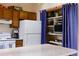 Cozy kitchen features wood cabinets, white appliances, and a pantry with shelving behind a blue curtain at 29101 Drexel Spur, Evergreen, CO 80439