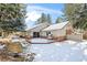 Back exterior of home with brick accents, a deck, and mature trees covered in snow at 4862 Silver Sage Ct, Boulder, CO 80301