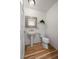 Cozy powder room featuring wood floors, a pedestal sink, and a decorative mirror, blending functionality with style at 4862 Silver Sage Ct, Boulder, CO 80301