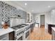 Close-up of a chef's kitchen featuring a large stainless steel range and custom backsplash at 3766 E Easter S Cir, Centennial, CO 80122