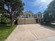 Traditional home featuring a three car garage, mature trees, and a large driveway with a sidewalk at 17130 Opal Hill Dr, Parker, CO 80134