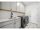 Well-equipped laundry room with white cabinets, gray washer/dryer, sink and tiled floor at 924 Sunflower St, Louisville, CO 80027