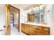 Bathroom featuring double sinks, oak vanity, large mirror, and access to bedroom and shower stall at 5723 S Kittredge St, Centennial, CO 80015