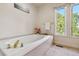 Bright bathroom featuring a soaking tub with gold fixtures and a large window at 2154 S Parfet Dr, Lakewood, CO 80227