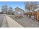 Landscaped front yard with gravel, a wooden fence, and mature trees at 8345 Moore St, Arvada, CO 80005