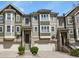 Exterior view of townhomes with brick and siding, garages, and landscaped entrances on a sunny day at 3680 S Beeler St # 5, Denver, CO 80237