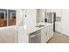 Modern kitchen island with stainless steel dishwasher and sink, white cabinets, and access to the back patio at 383 Remuda Rd, Berthoud, CO 80513