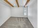 Simple, clean bedroom with neutral carpet, white walls, wooden beam ceiling, and a bright window at 4365 S Alton Way, Greenwood Village, CO 80111
