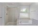 Bathroom with glass enclosed shower and a soaking tub under an arched window at 5403 Odessa St, Denver, CO 80249